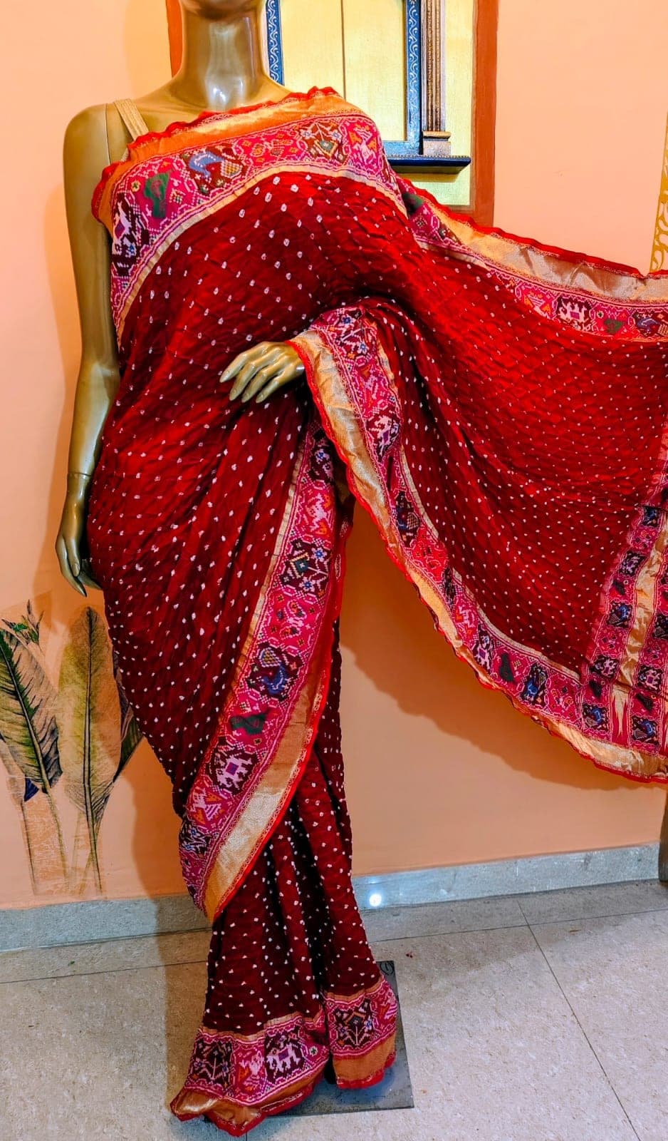 Vermilion saree with a pink figured border, on a stand