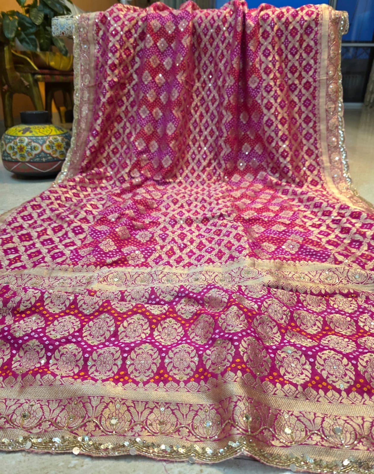 Magenta bandhej saree with a gold-zari lattice, spread out